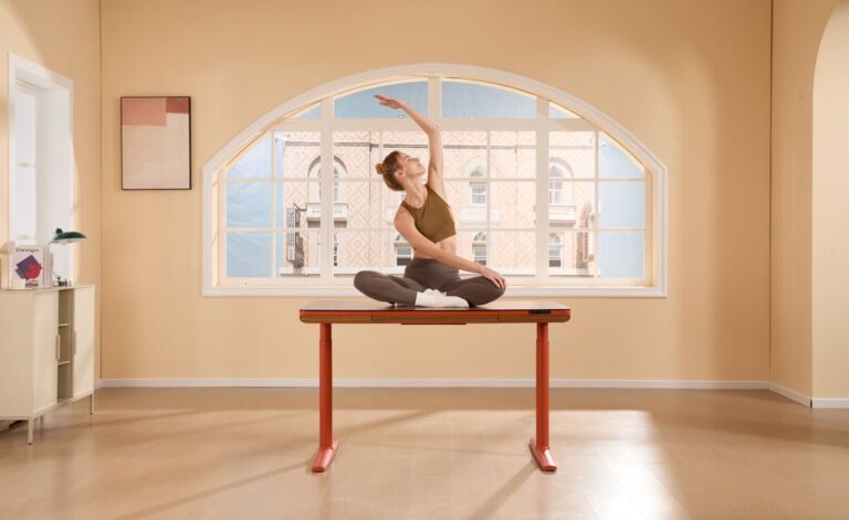 Woman practising a simple yoga movement beside a desk in a modern office