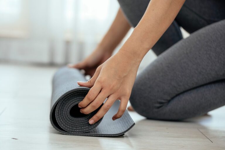 Woman unrolling a lightweight yoga mat in a bright indoor space