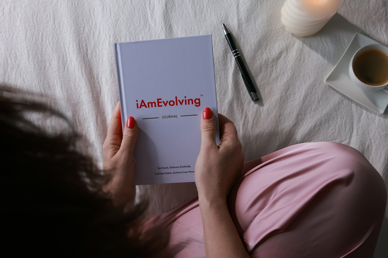 Hands holding a journal beside a pen and warm indoor light