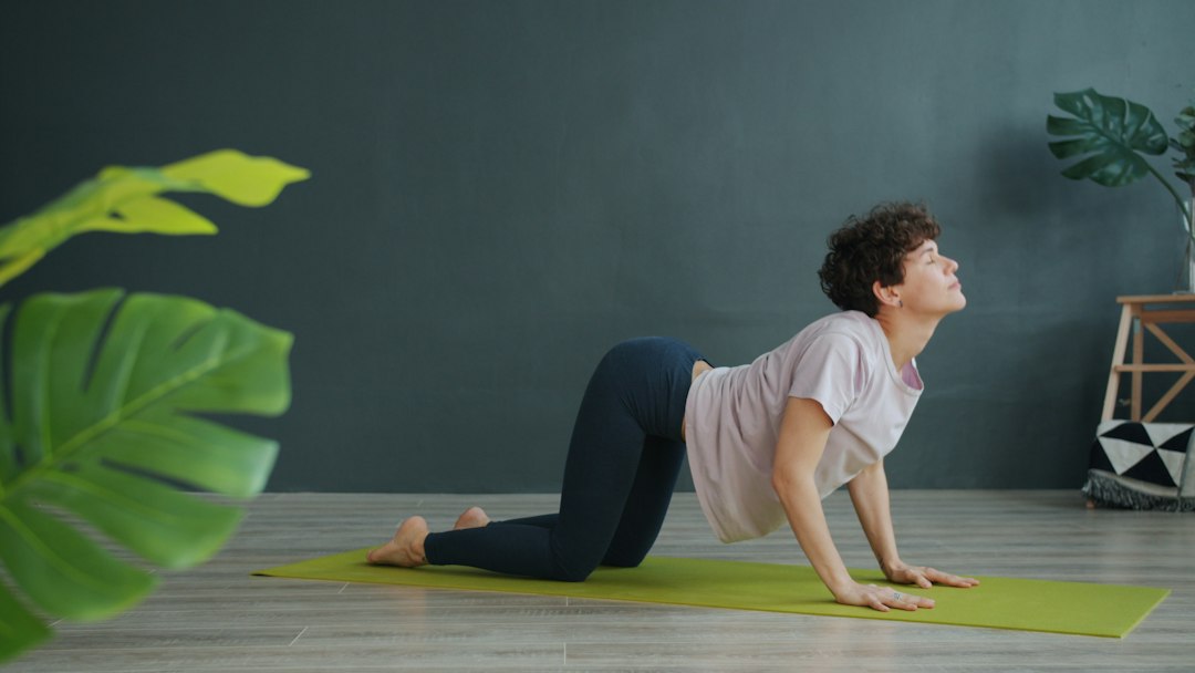 Person practising a spinal movement on a yoga mat