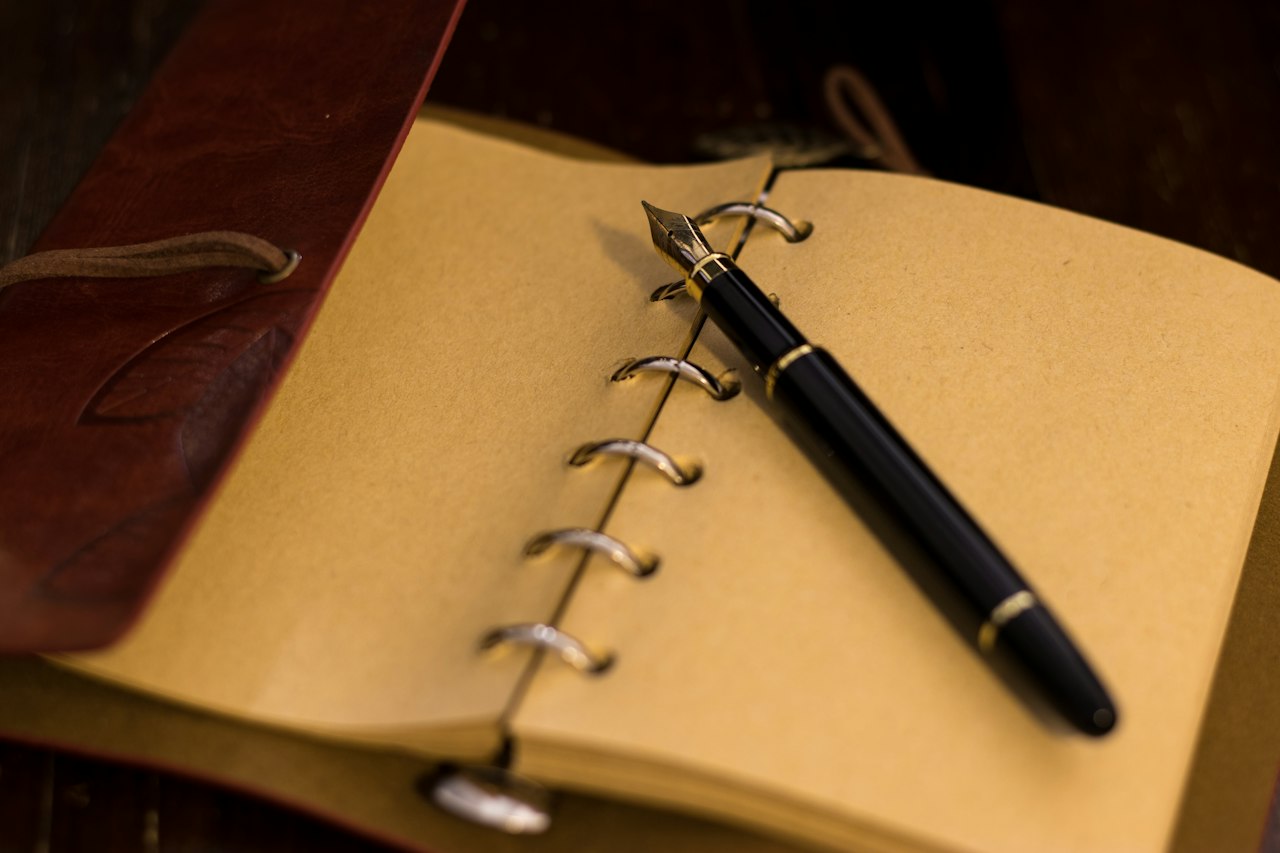 Notebook with a pen laid across its pages